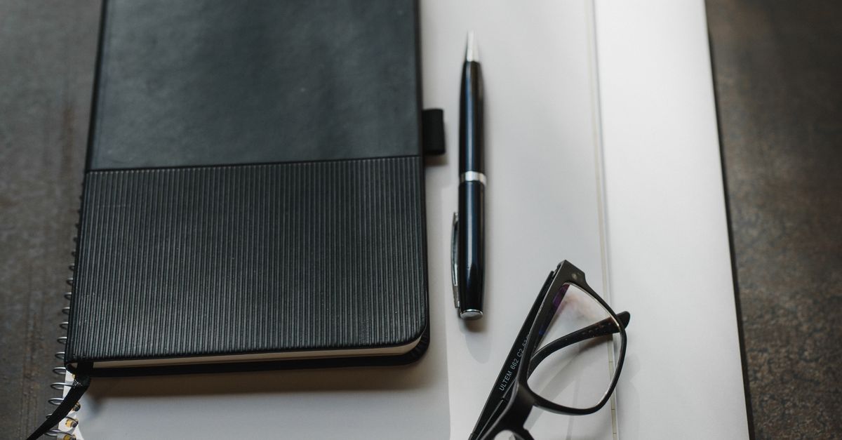 stack of notebooks with pen